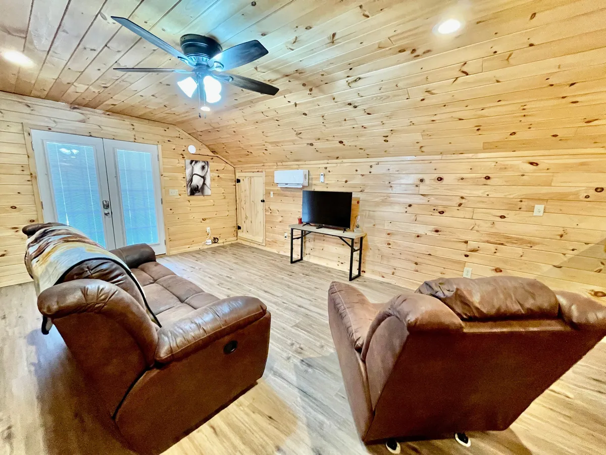 This image shows a comfortable interior living area with leather recliners, a wooden ceiling, and double doors that open to the outdoors. The space is inviting and suggests an easy transition between indoor coziness and outdoor adventure.