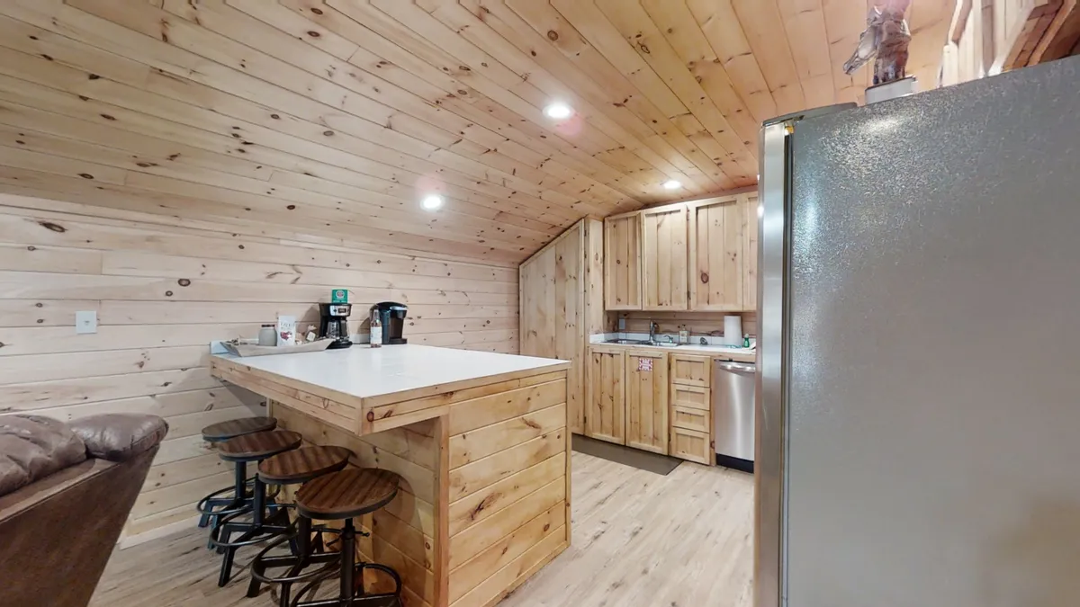 A cozy kitchen scene with a wooden countertop, visible appliances, and bar stools inviting guests to gather near the cooking area. The setup highlights a welcoming environment for both cooking and enjoying casual meals or morning coffee.