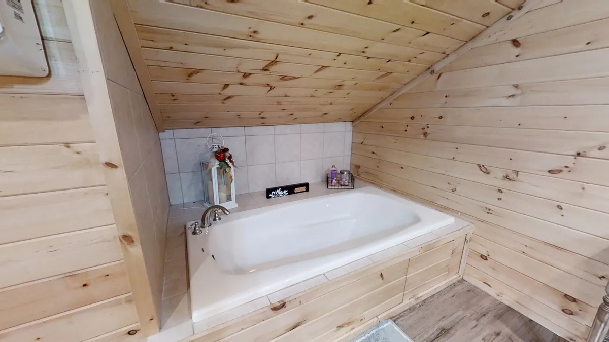 A tranquil bathroom scene featuring a large soaking bathtub set against wooden walls, accented by decorative items that create a spa-like ambiance. The space invites relaxation and self-care routines, ideal for restorative soaks.